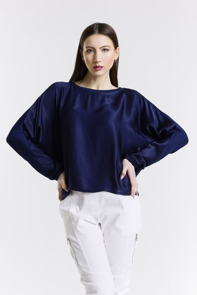 Woman wearing a navy blue blouse and white pants on a white background