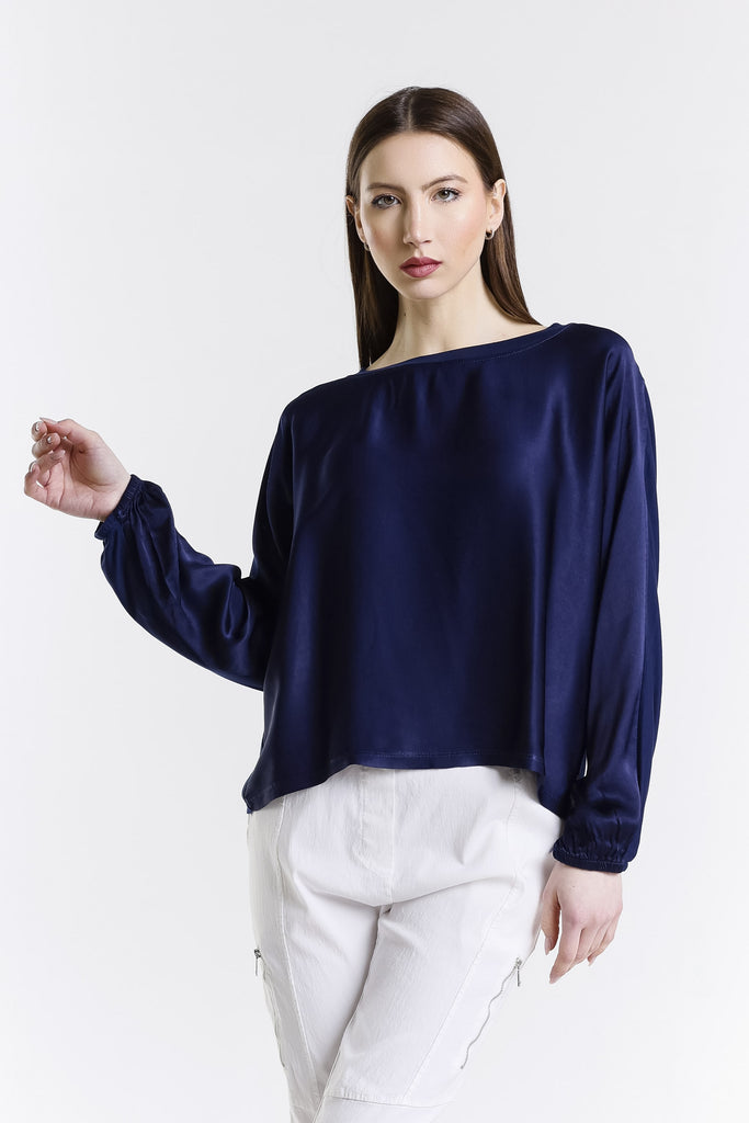 Woman wearing a navy blue top and white pants on a white background