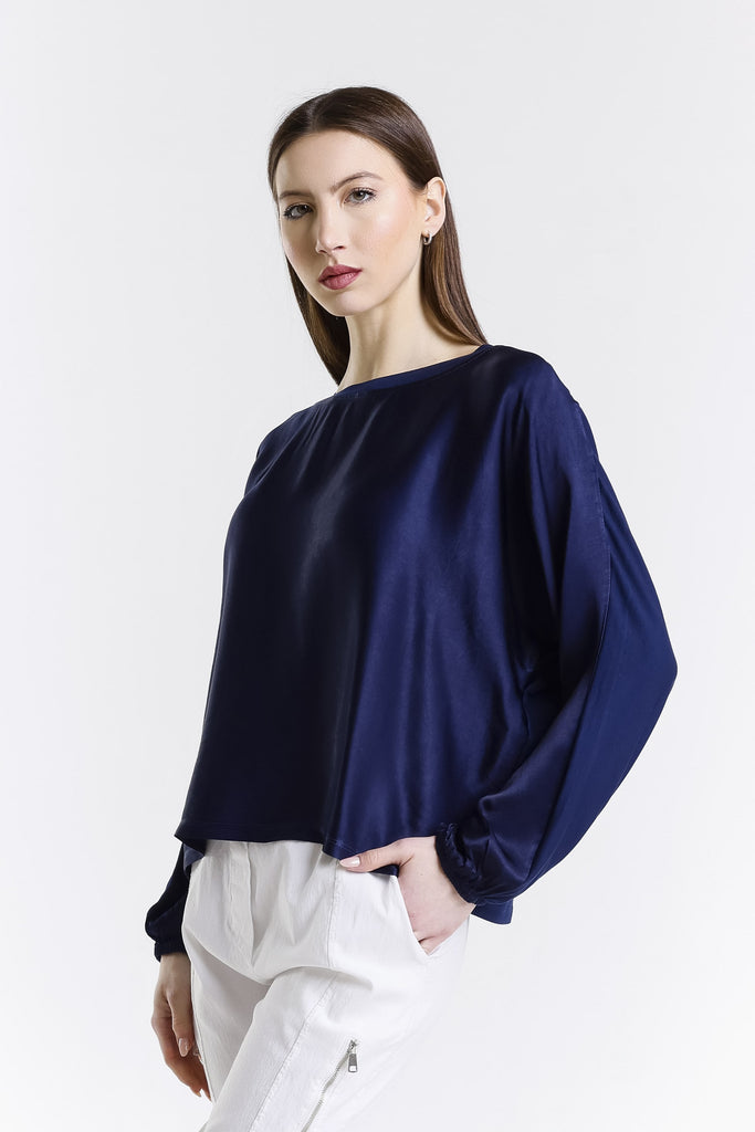 Woman wearing a navy blue blouse and white pants on a white background