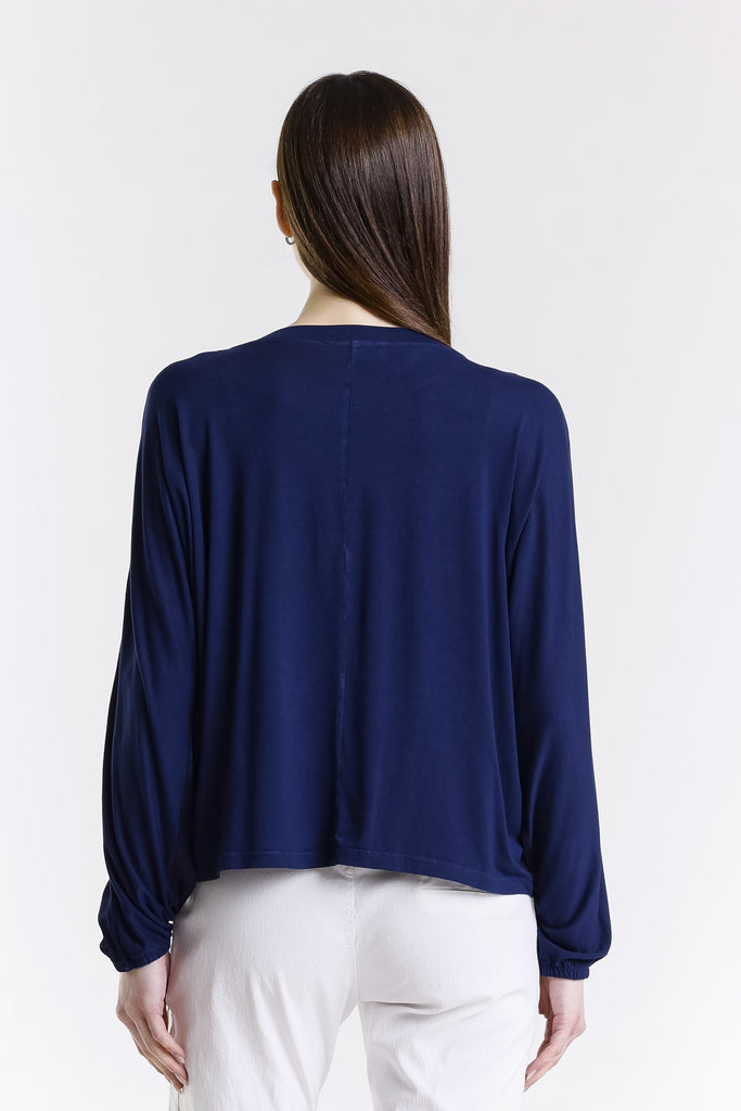 Woman wearing a navy blue top and white pants on a white background
