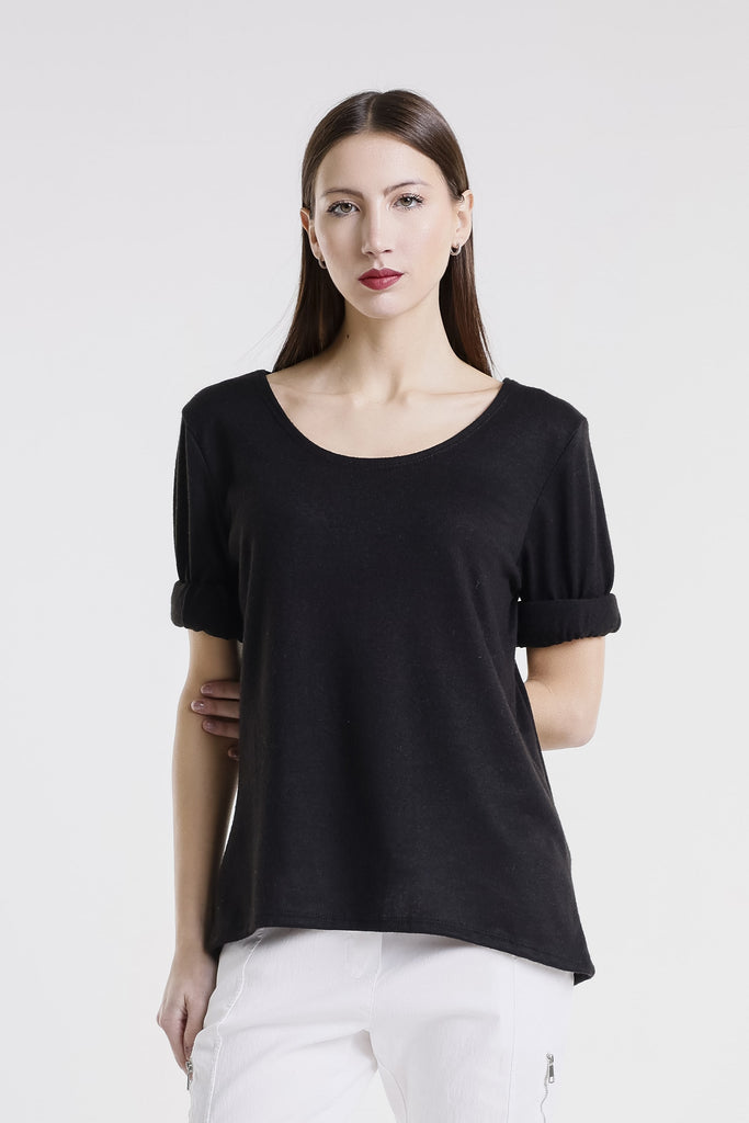 Woman wearing a black top and white pants against a white background