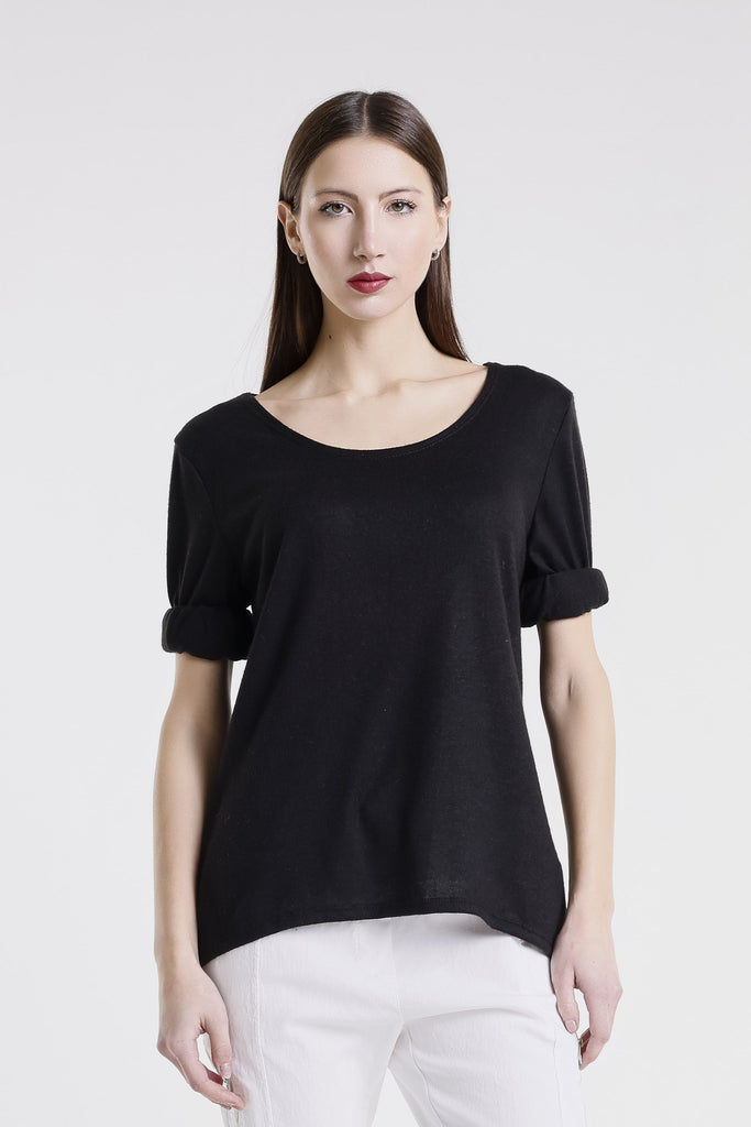 Woman wearing a black top and white pants against a white background