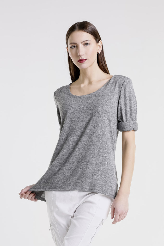 Woman wearing a gray top and white pants on a white background