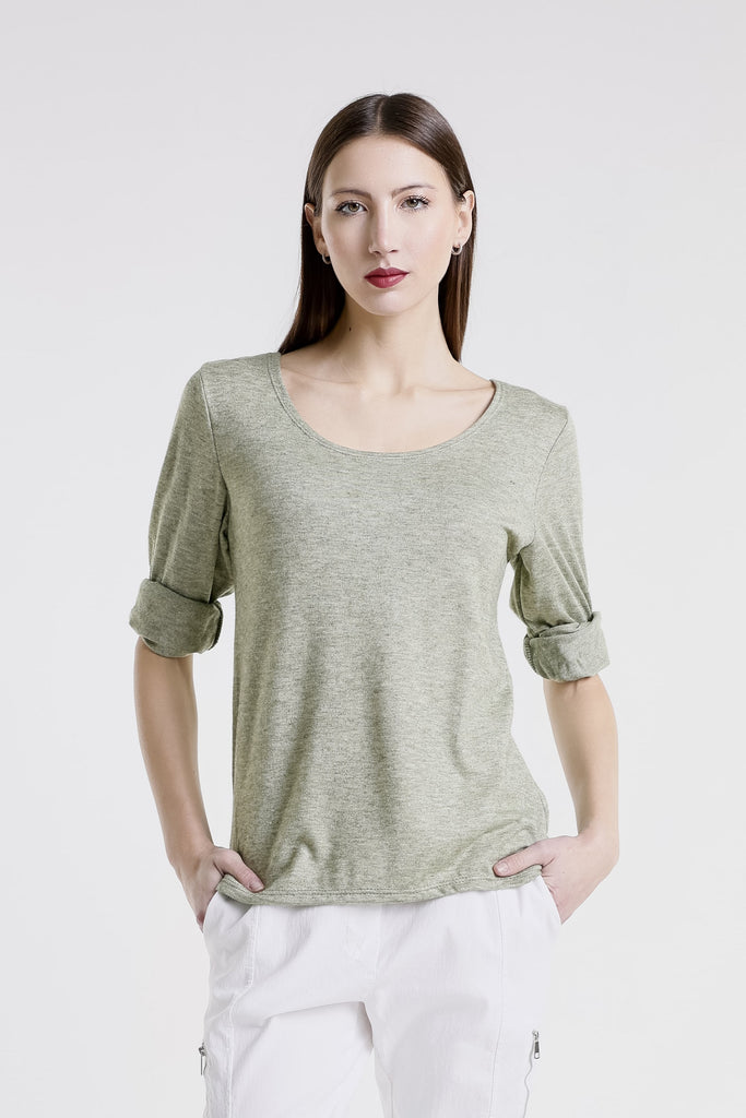 Woman wearing a green sweater and white pants on a white background