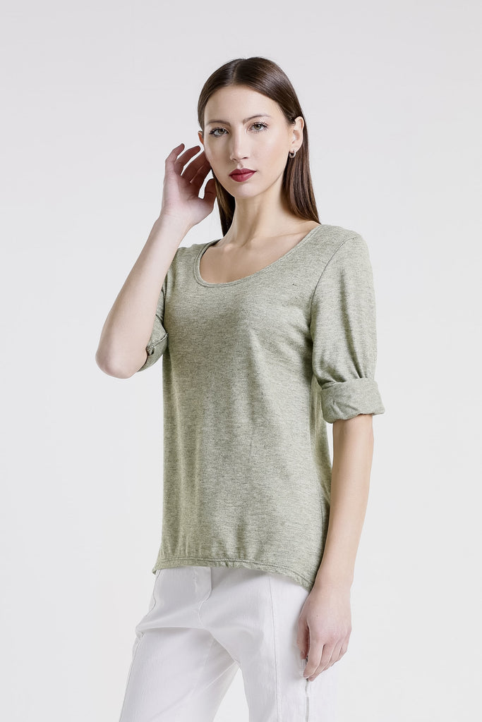 Woman wearing a green top and white pants on a light gray background
