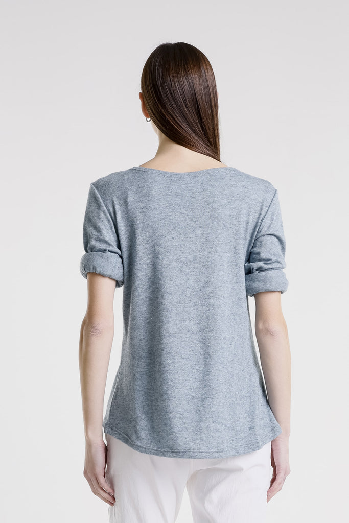 Woman wearing a light gray t-shirt with rolled-up sleeves on a white background
