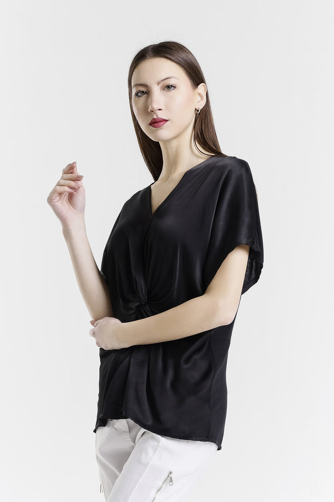 Woman wearing a black blouse and white pants on a white background
