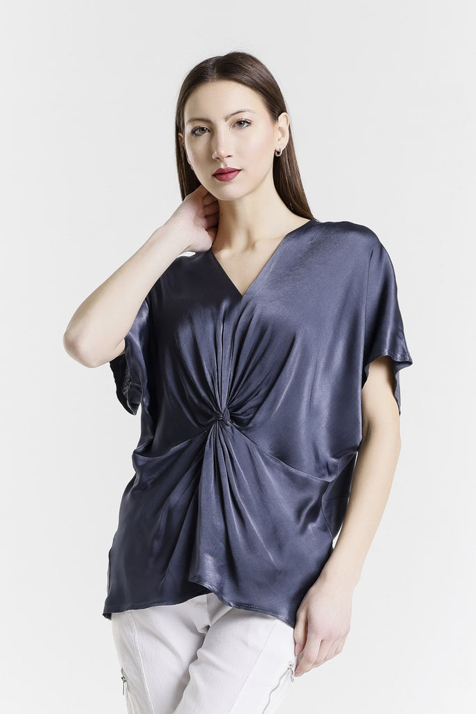 Woman wearing a dark gray blouse with a knot detail on a white background