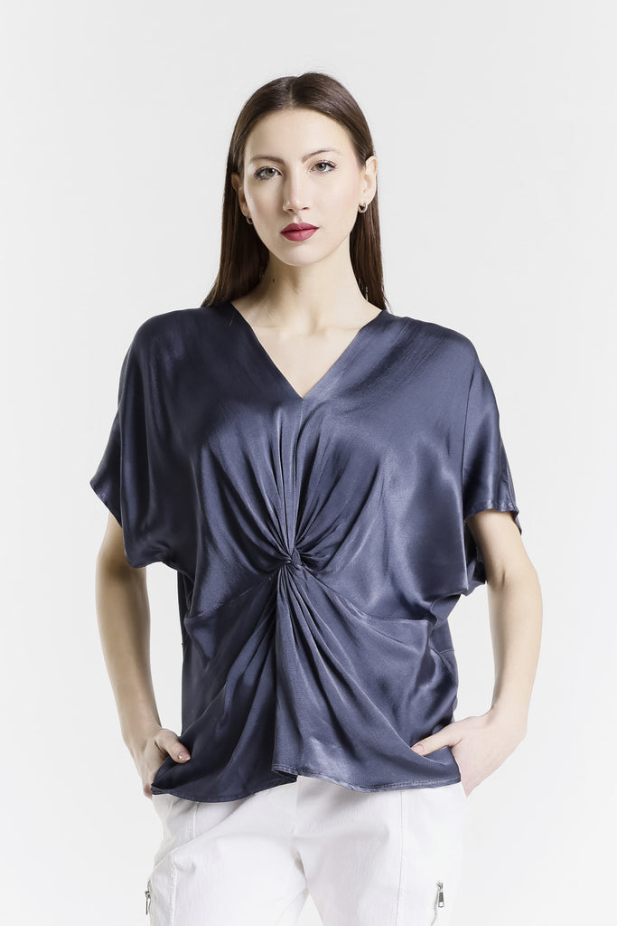 Woman wearing a dark blue top with a knot detail on a white background