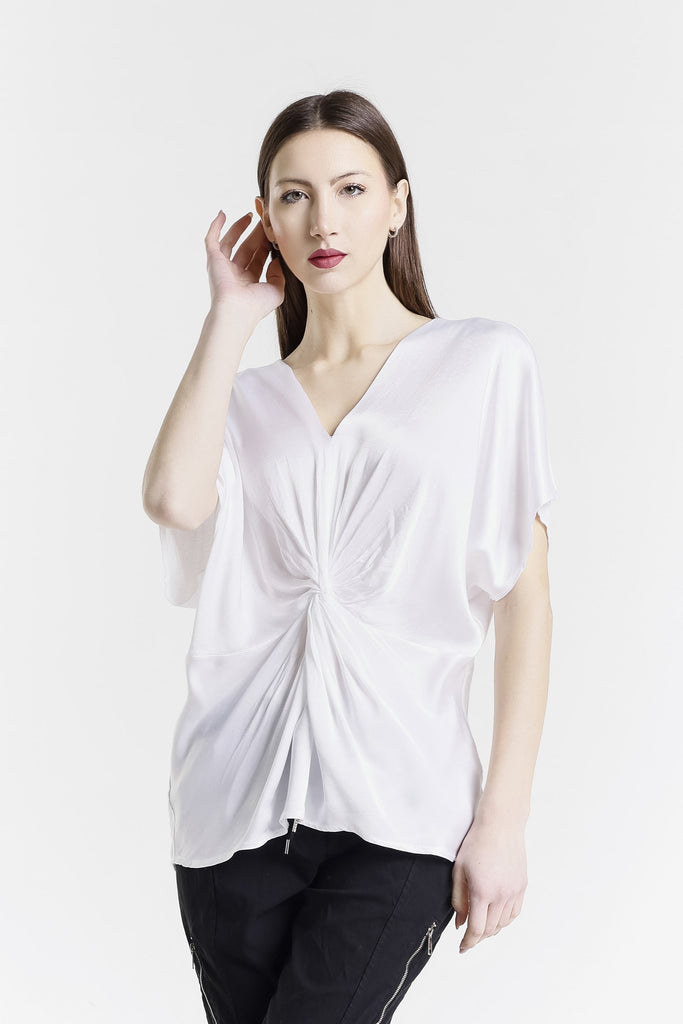 Woman wearing a white blouse with a knot detail on a white background