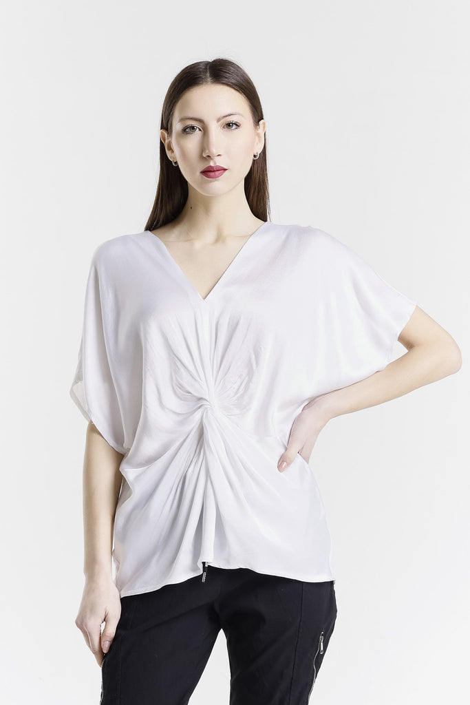Woman wearing a white blouse with a knot detail on a white background