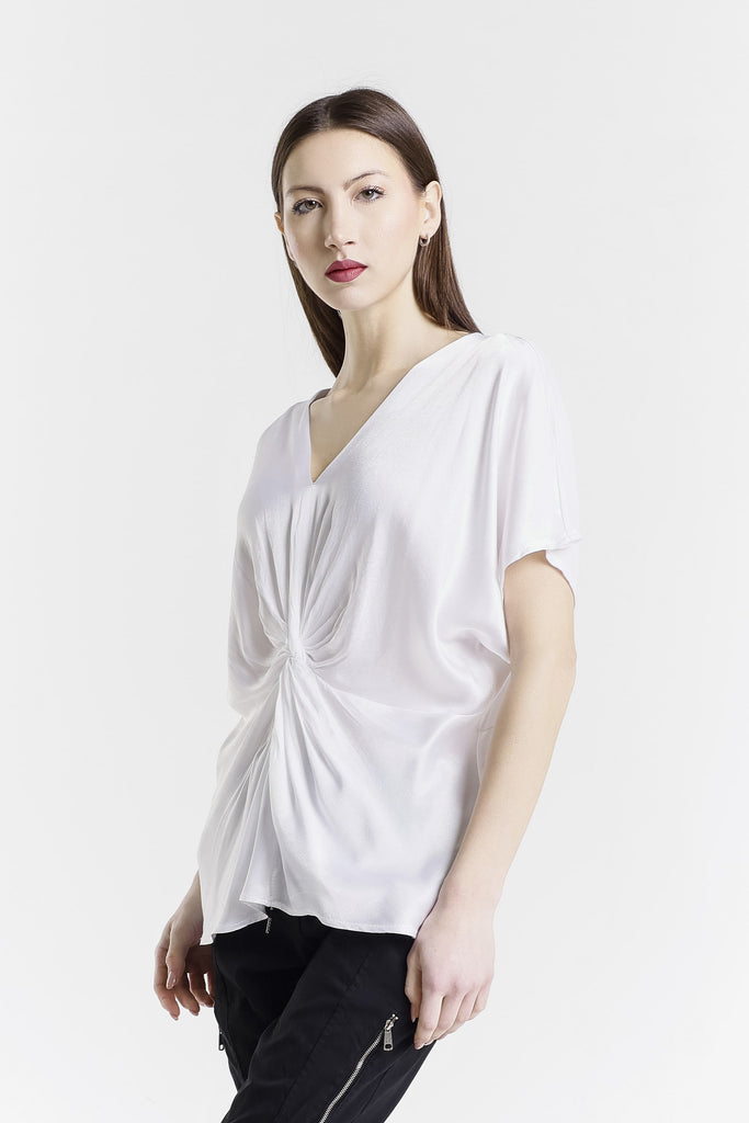 Woman wearing a white blouse with a knot detail on a white background