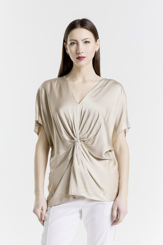 Woman wearing a beige top with a knot detail on a white background