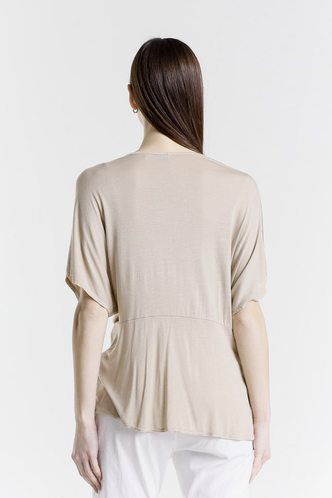 Woman wearing a beige top with a plain white background