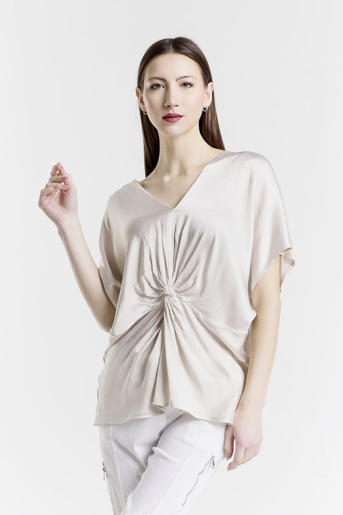 Woman wearing a beige top with a knot detail on a white background