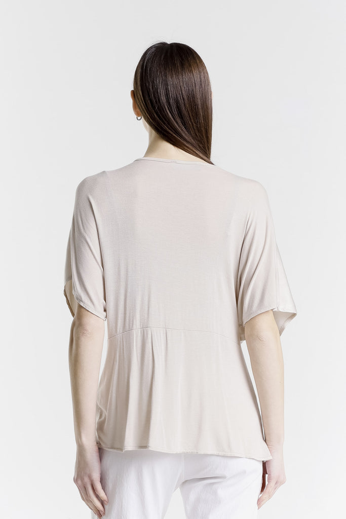 Woman wearing a beige blouse with sheer sleeves on a white background