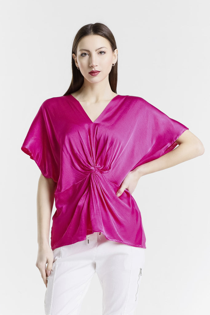 Woman wearing a bright pink top with a knot detail on a white background