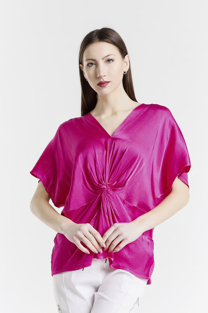 Woman wearing a bright pink blouse with a knot detail on a white background