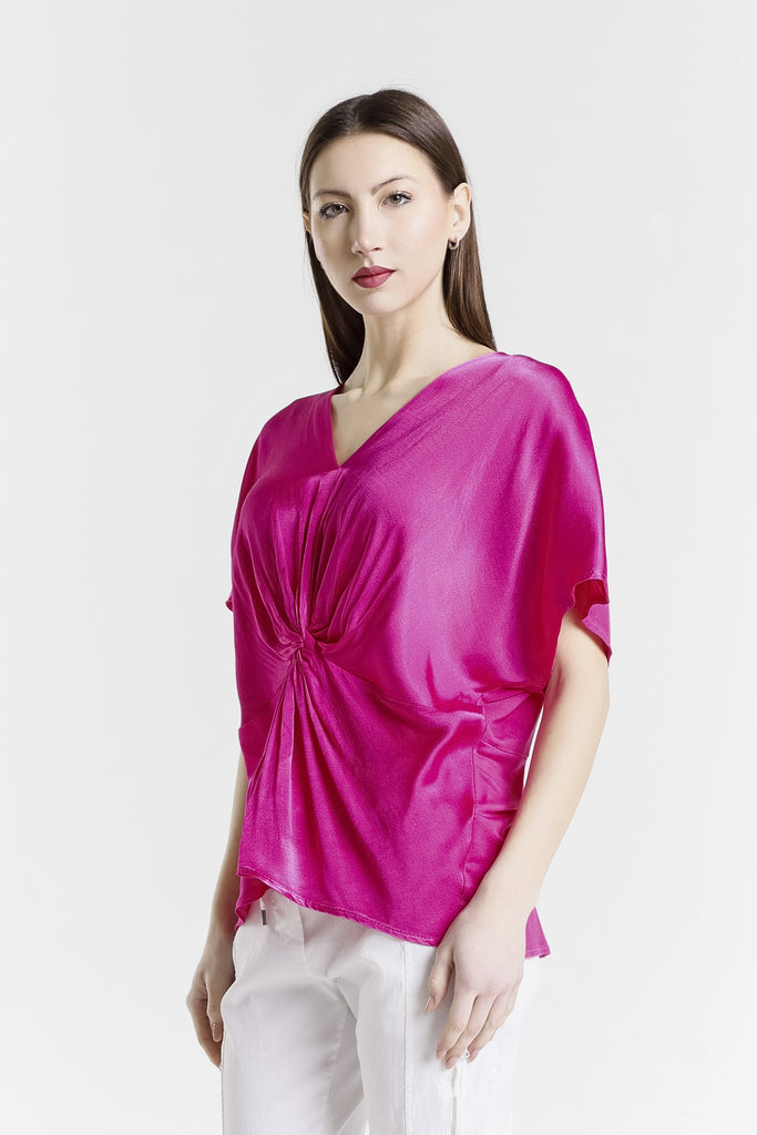 Woman wearing a bright pink blouse with a white background