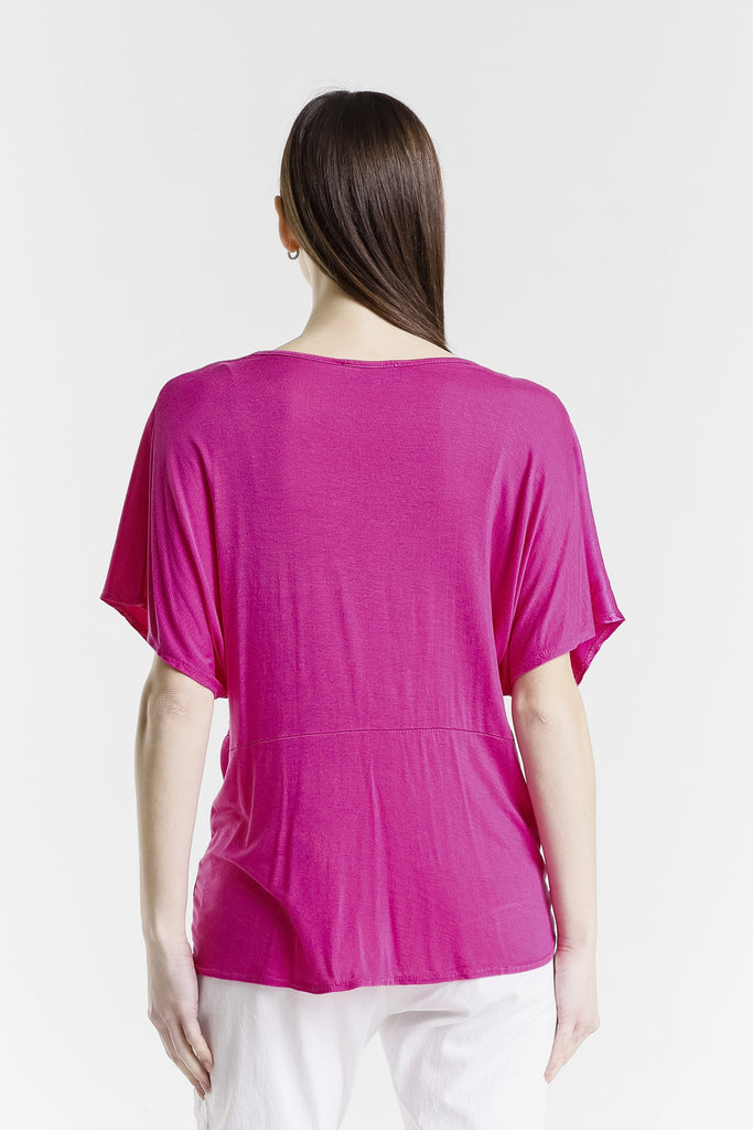 Person wearing a bright pink top and white pants on a white background