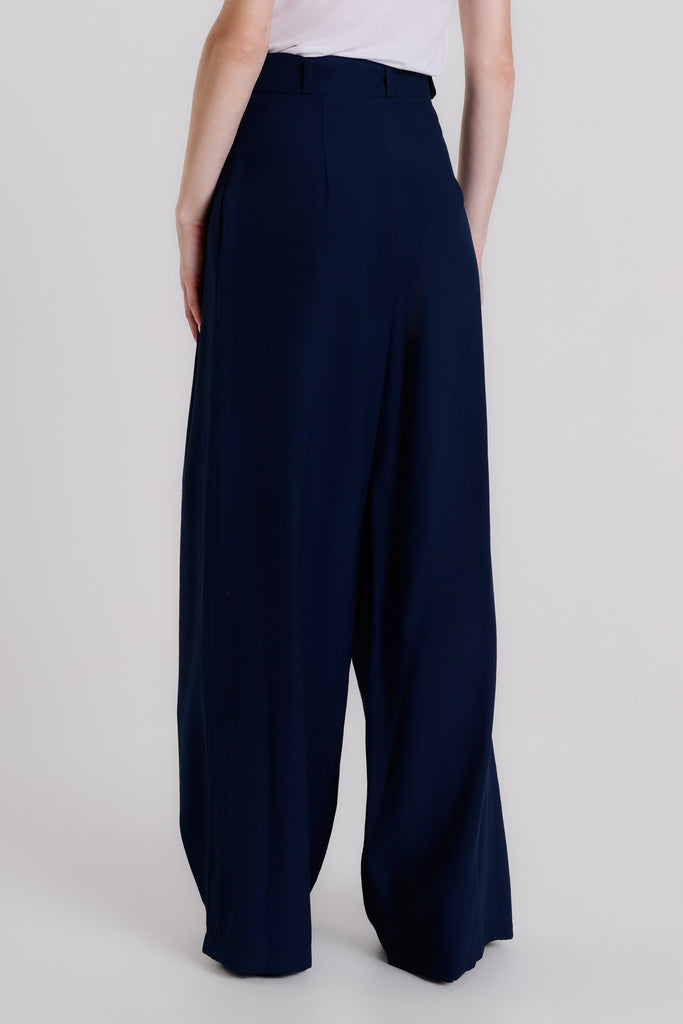 Navy wide-leg pants worn by a person on a light gray background